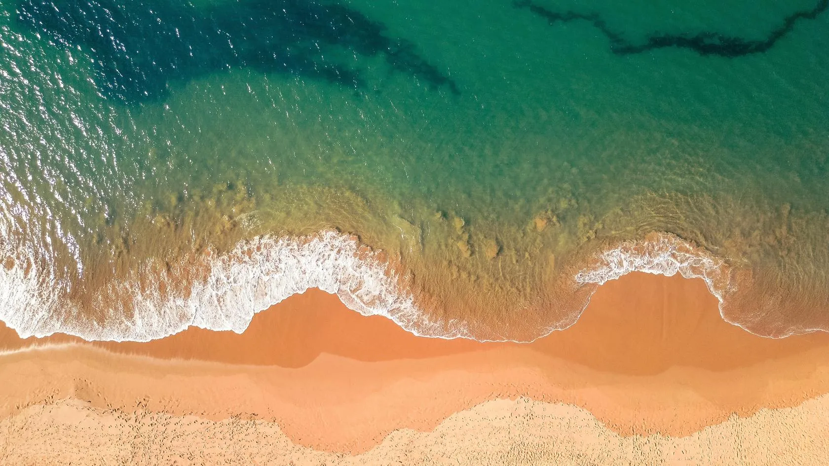Aerial view of the turquoise water and golden sand of a Northern Beaches beach